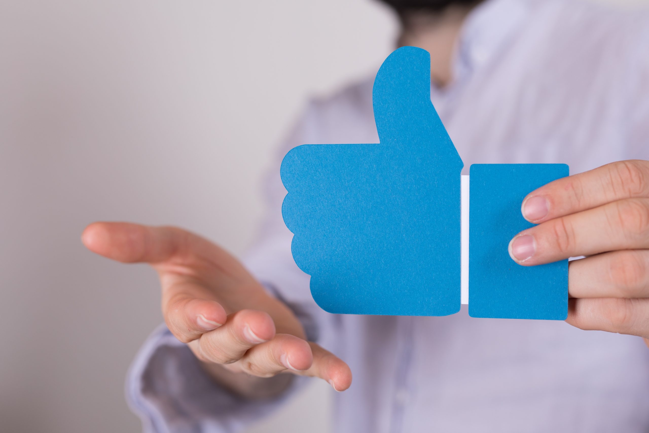 A closeup shot of a person holding a blue thumbs-up sign under the lights